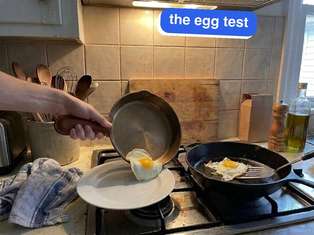 Two pans on my stove: the iLume, held by its leather handle cover, sliding its egg out whole onto a plate; the Lodge's egg stuck and torn under a spatula.